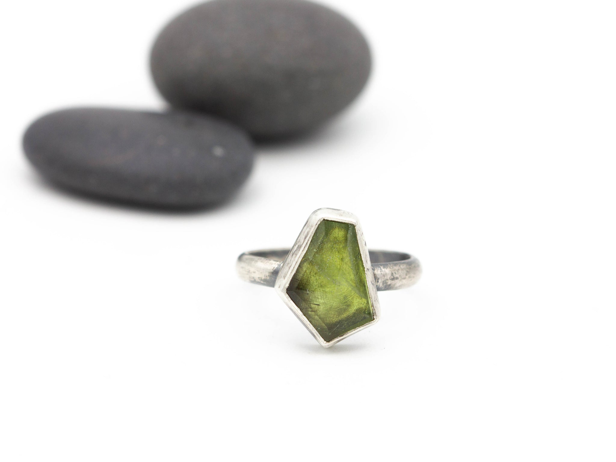 Five-sided green peridot stone with tiny black inclusions set in sterling silver as a ring